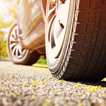 Car tires closeup on asphalt road on summer day at park. Vehicle outdoors in nature with beautiful sunlight near Long Branch, NJ.