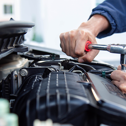 Mechanic near Ocean Township working on repairing a car’s engine with a wrench.