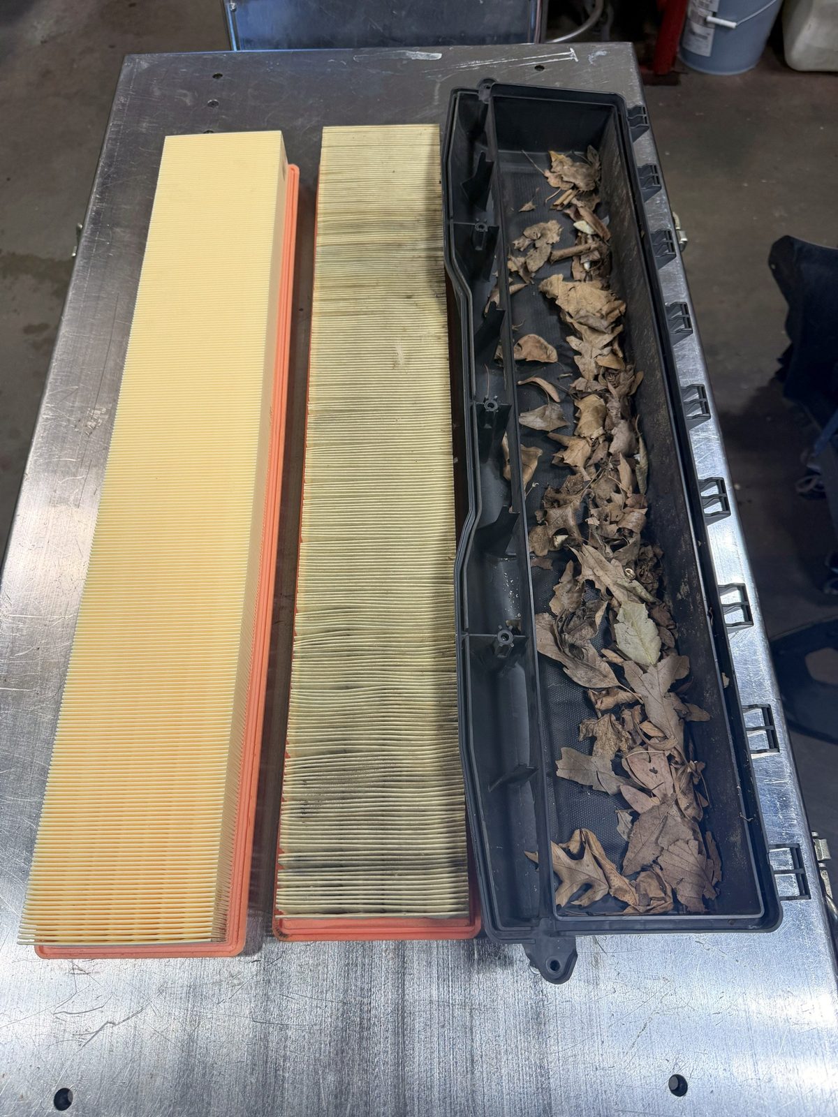 Leaves packed in the air box of a 2018 Porsche Panamera 4S next to the old and new air filters, Massimo Motorworks Shrewsbury NJ
